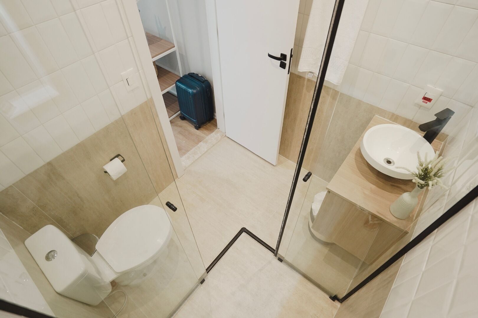 Un baño moderno con cabina de ducha de vidrio, un lavabo blanco y un inodoro.