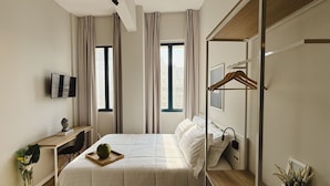 A modern hotel room with a bed, a desk, a TV, and a mirror. - Apê Santos Gonzaga (Santos)