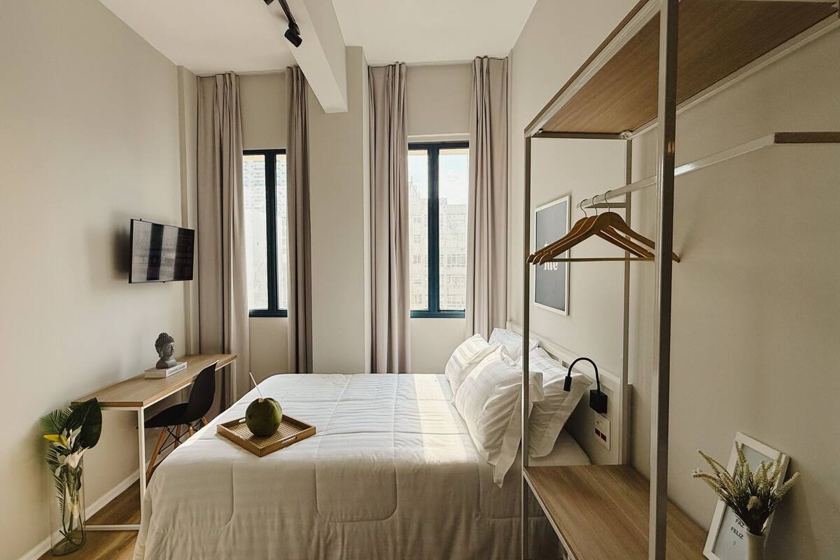 Ein modernes Hotelzimmer mit Bett, Schreibtisch, Fernseher und Spiegel.