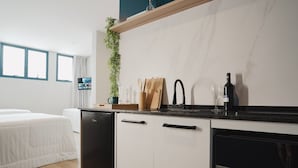 A modern kitchen with a built-in dishwasher, a wine glass, and a plant on the counter. - Apê Santos Gonzaga (Santos)