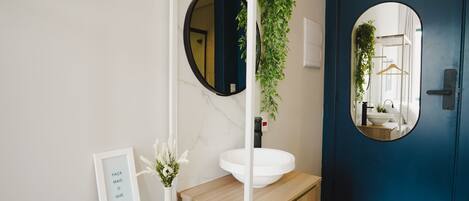 A bathroom with a white sink, a round mirror, and a blue door.