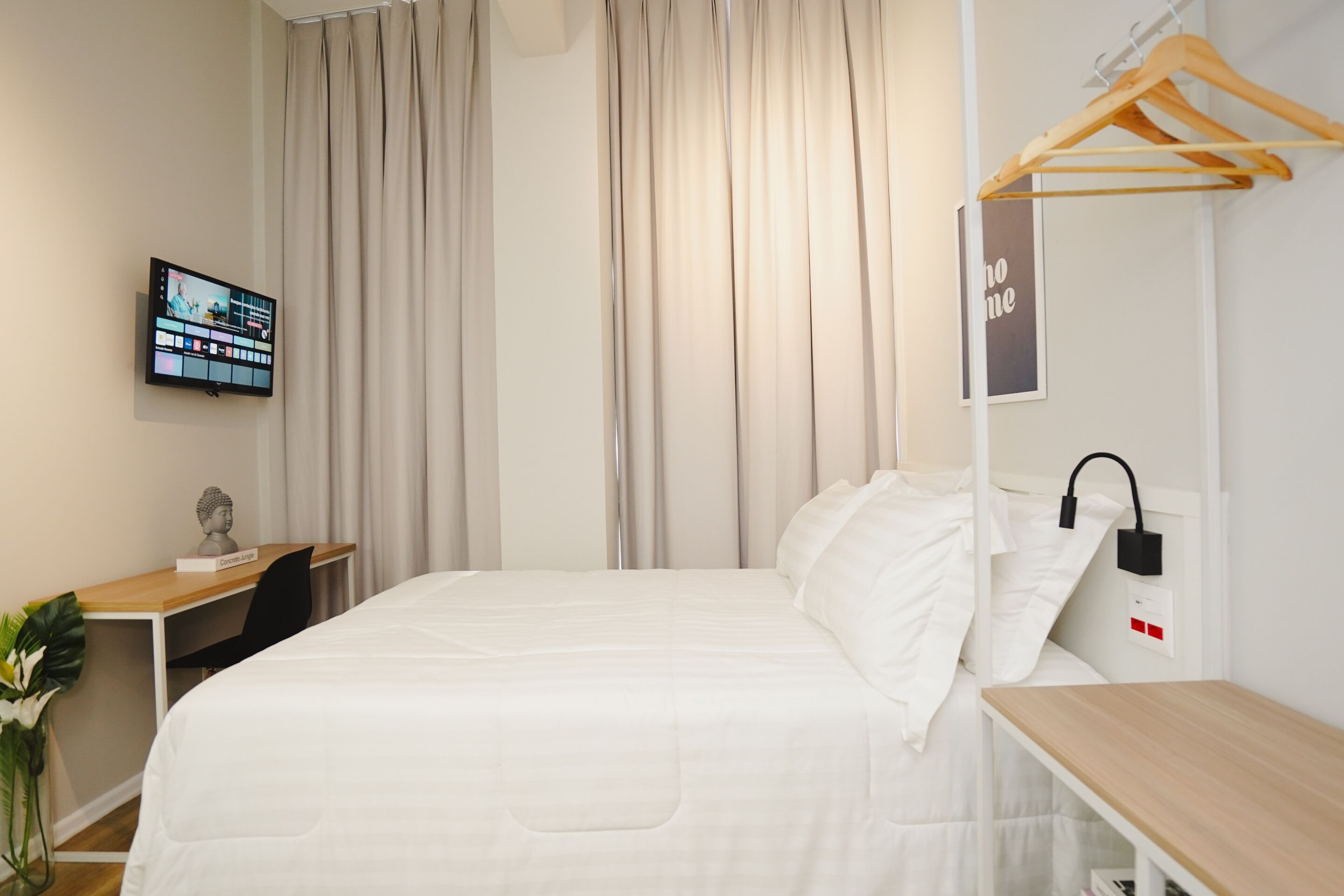 A neatly arranged hotel room with a bed, a desk, a chair, a TV, and a wardrobe.