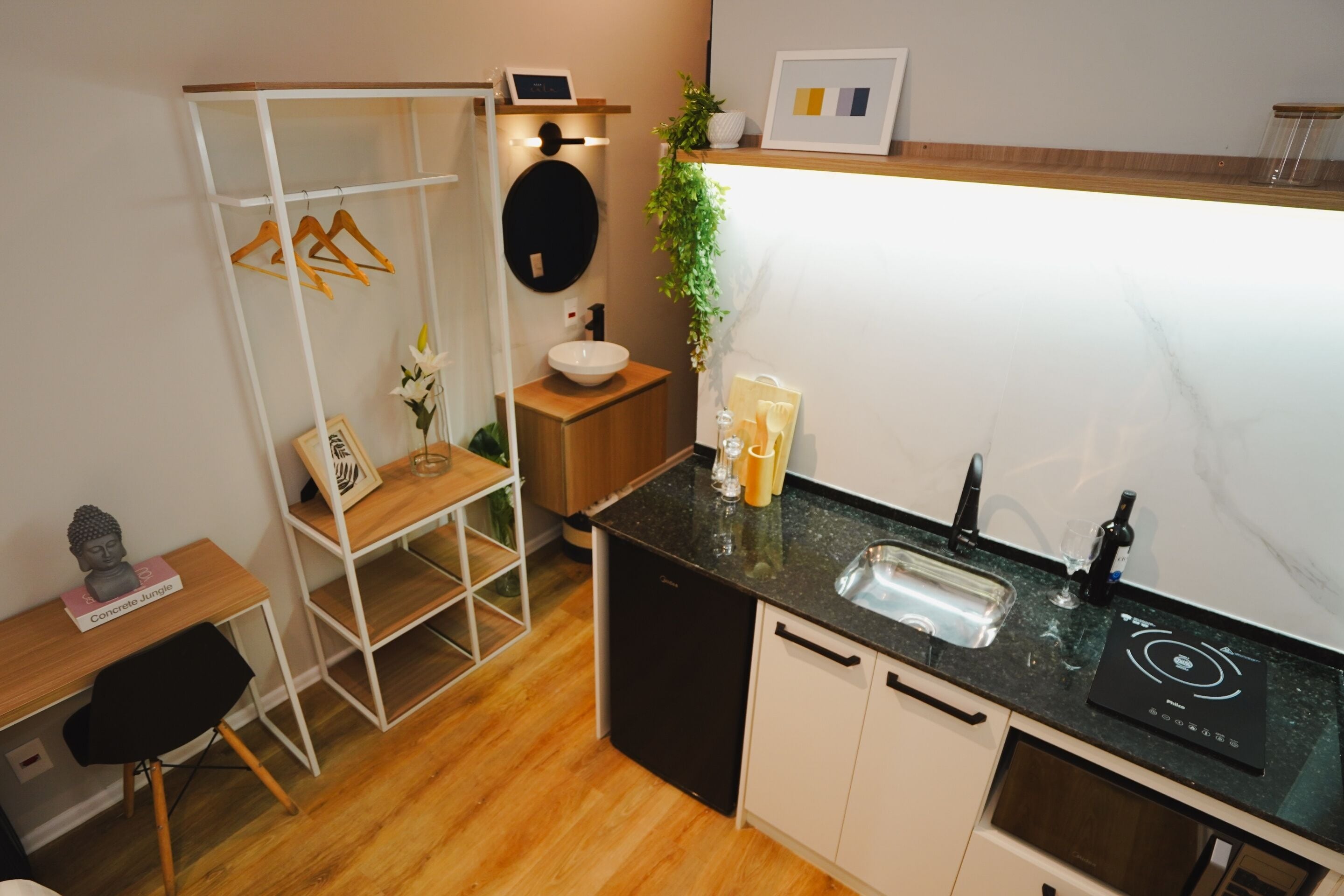 A compact kitchen with a black countertop, white cabinets, a built-in dishwasher, and a small sink.