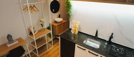A compact kitchen with a black countertop, white cabinets, a built-in dishwasher, and a small sink.