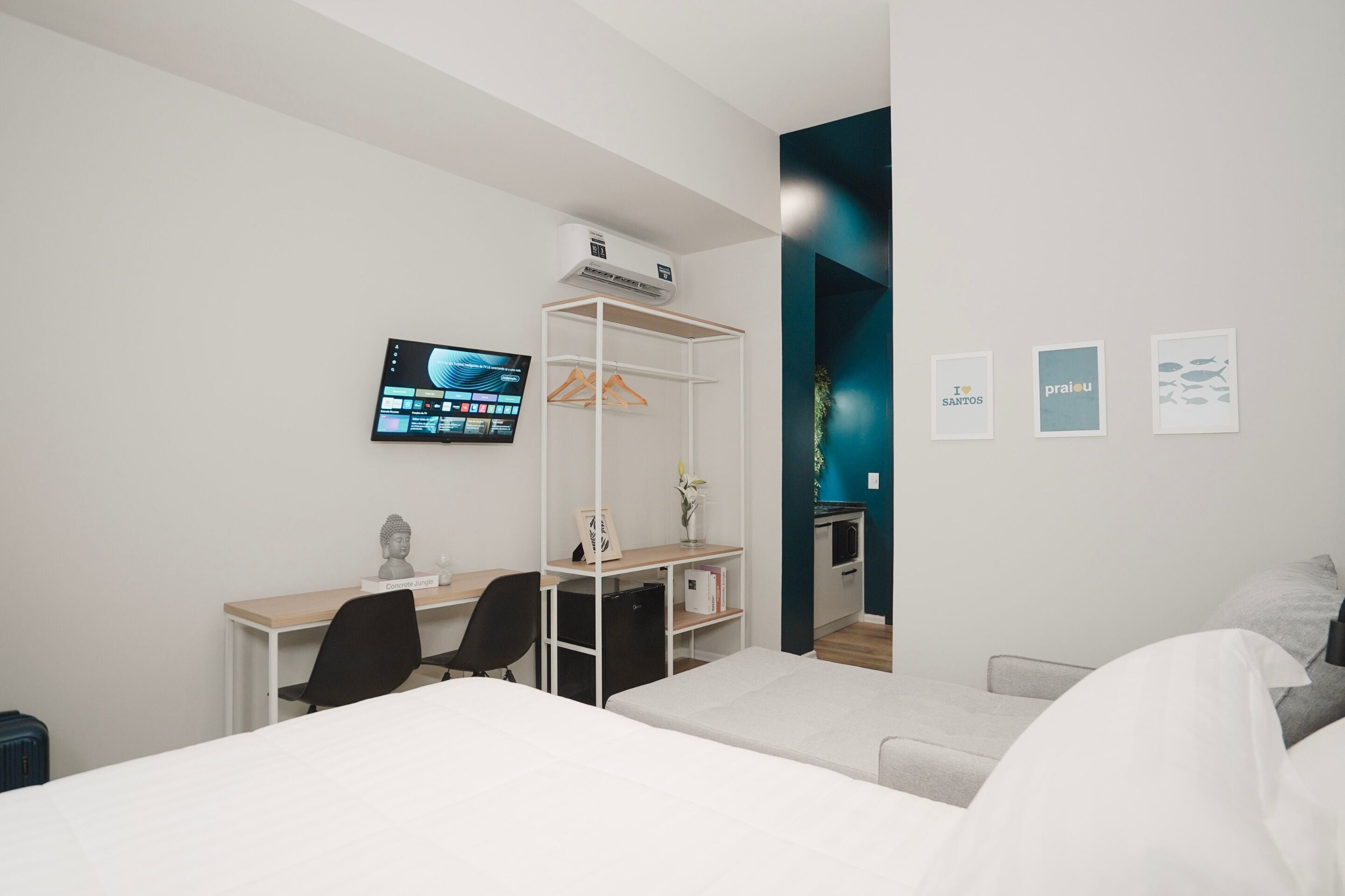 A modern hotel room with a bed, a desk, a chair, a TV, and a wardrobe.