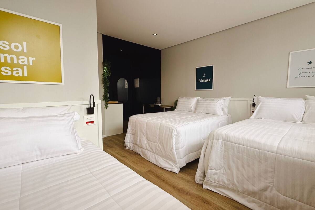 Ein Hotelzimmer mit zwei Betten, einem Schreibtisch und einem Stuhl. An der Wand hängt ein Schild und ein gerahmtes Bild.