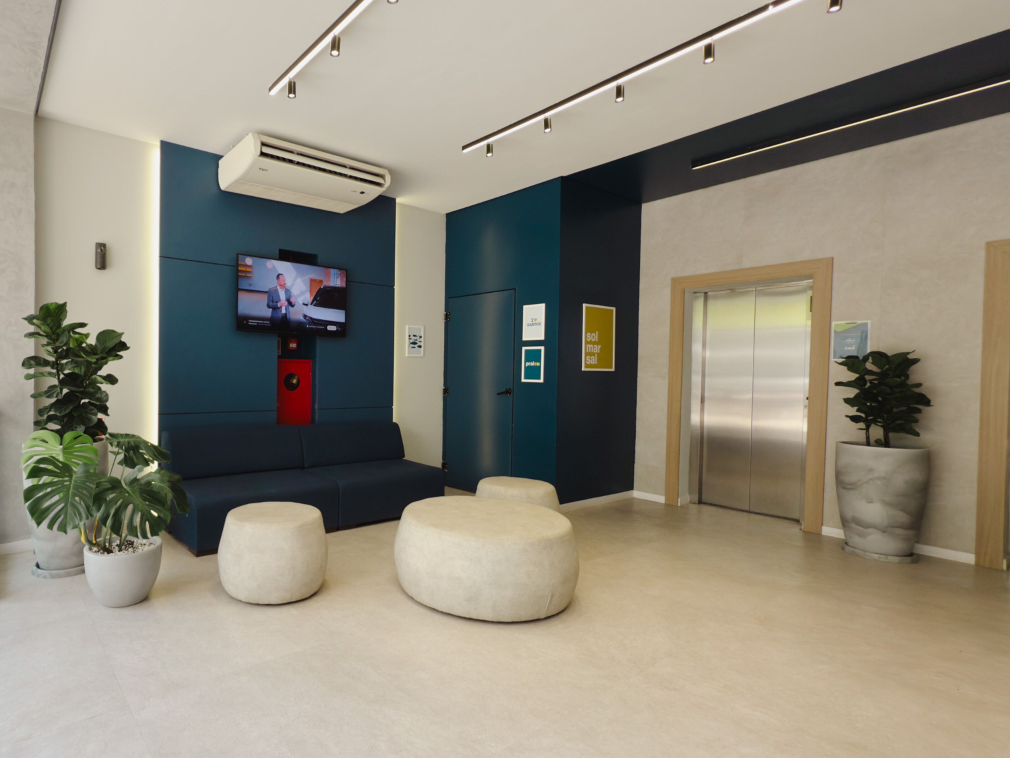 A modern lobby with a flat-screen TV, a sofa, and a reception desk.