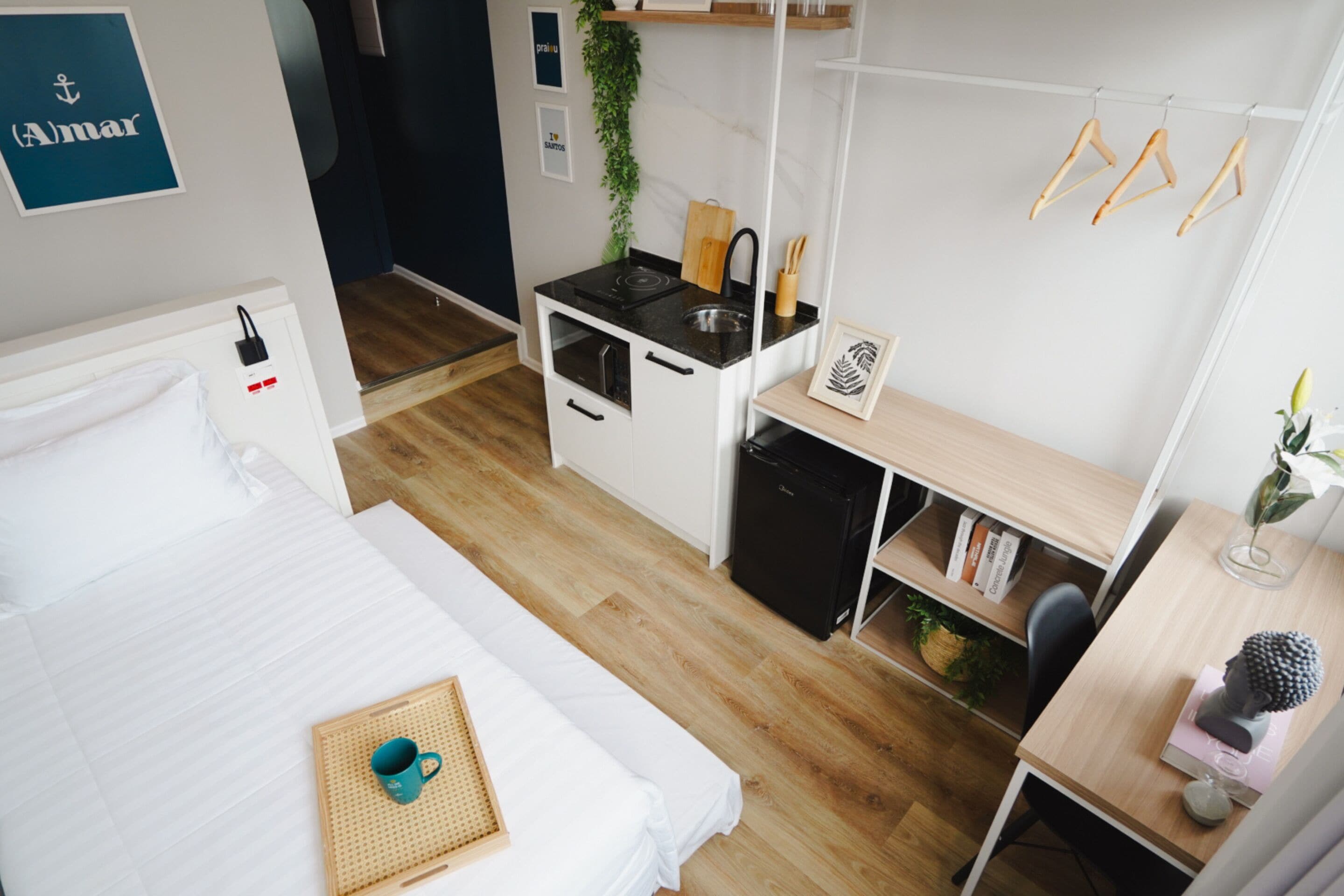 A compact room with a bed, kitchenette, and a desk.