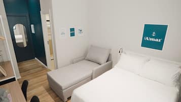 A hotel room with a bed, a sofa, a desk with a chair, and a mirror.