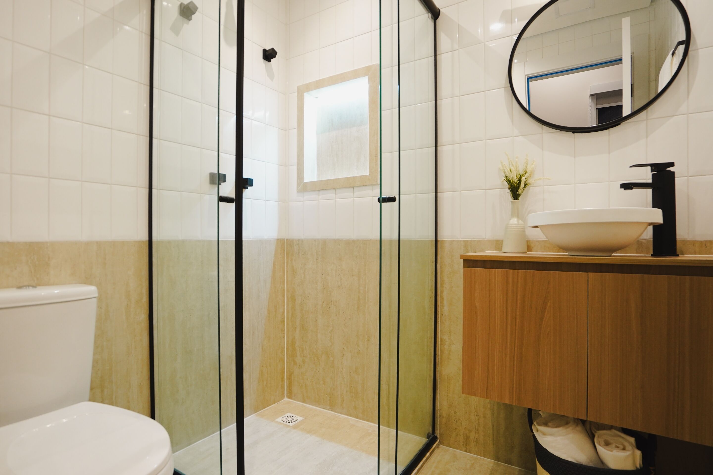 A modern bathroom with a glass shower enclosure, a white toilet, a wooden vanity with a sink, and a mirror.