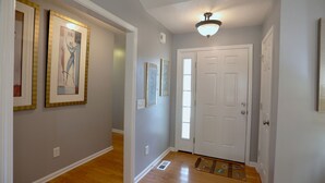 A hallway with framed artwork on the walls, a white door, and a light fixture above it. - 4-bedroom house in lovely Aberdeen so close to Pinehurst (Aberdeen)