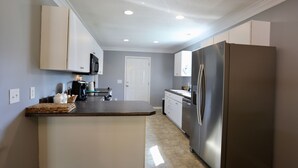 A compact kitchen with a central island, built-in appliances, and a door leading to another room. - 4-bedroom house in lovely Aberdeen so close to Pinehurst (Aberdeen)