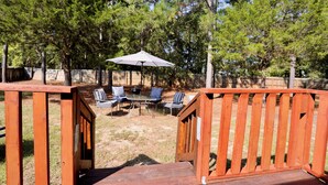 A wooden deck with a table and chairs under a striped umbrella, surrounded by trees. - 4-bedroom house in lovely Aberdeen so close to Pinehurst (Aberdeen)