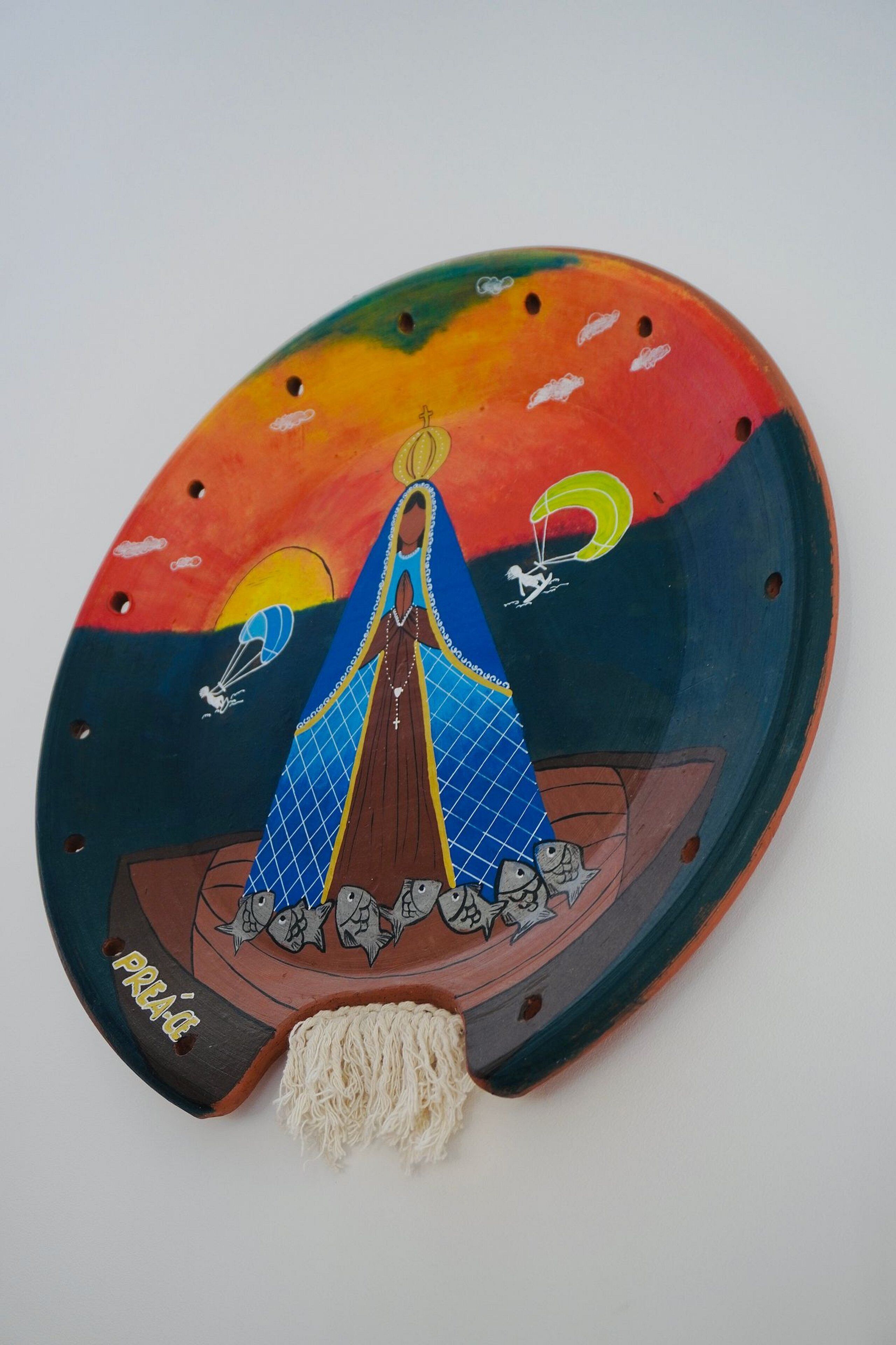 A colorful wooden plaque with a religious figure, a boat, and fish.