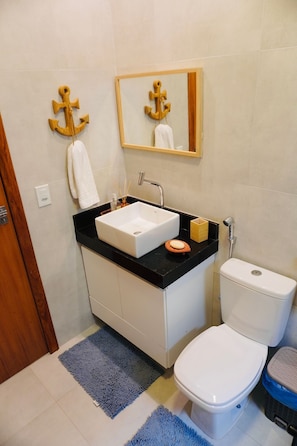 A bathroom with a white sink, a toilet, and a mirror above the sink. - Casacharm - Praia do Preá (Cruz)