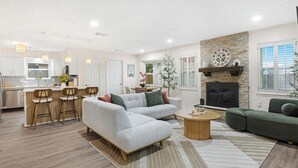 A spacious living area with a sofa, a coffee table, and a fireplace. There is a kitchen area with a dining table and bar stools. - Relaxing Japandi Stay - Pool - Houston Stafford (Stafford)