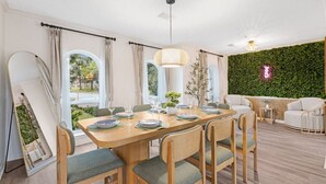A dining area with a wooden table set for six, surrounded by chairs with green cushions. - Relaxing Japandi Stay - Pool - Houston Stafford (Stafford)