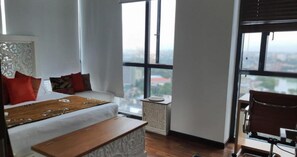 Relax in a spacious room with a large bed, featuring a comfortable headboard and plush pillows, and take in the city views from the large windows.