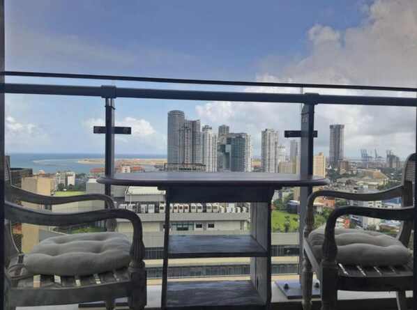 Enjoy breathtaking views of the city from this balcony with a table and two chairs.