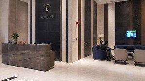 A modern reception area with a marble reception desk, a seating area with sofas, and a television screen. - Capitol Twinpeaks Colombo 2 Sri Lanka Vacation rental - long term (Colombo)