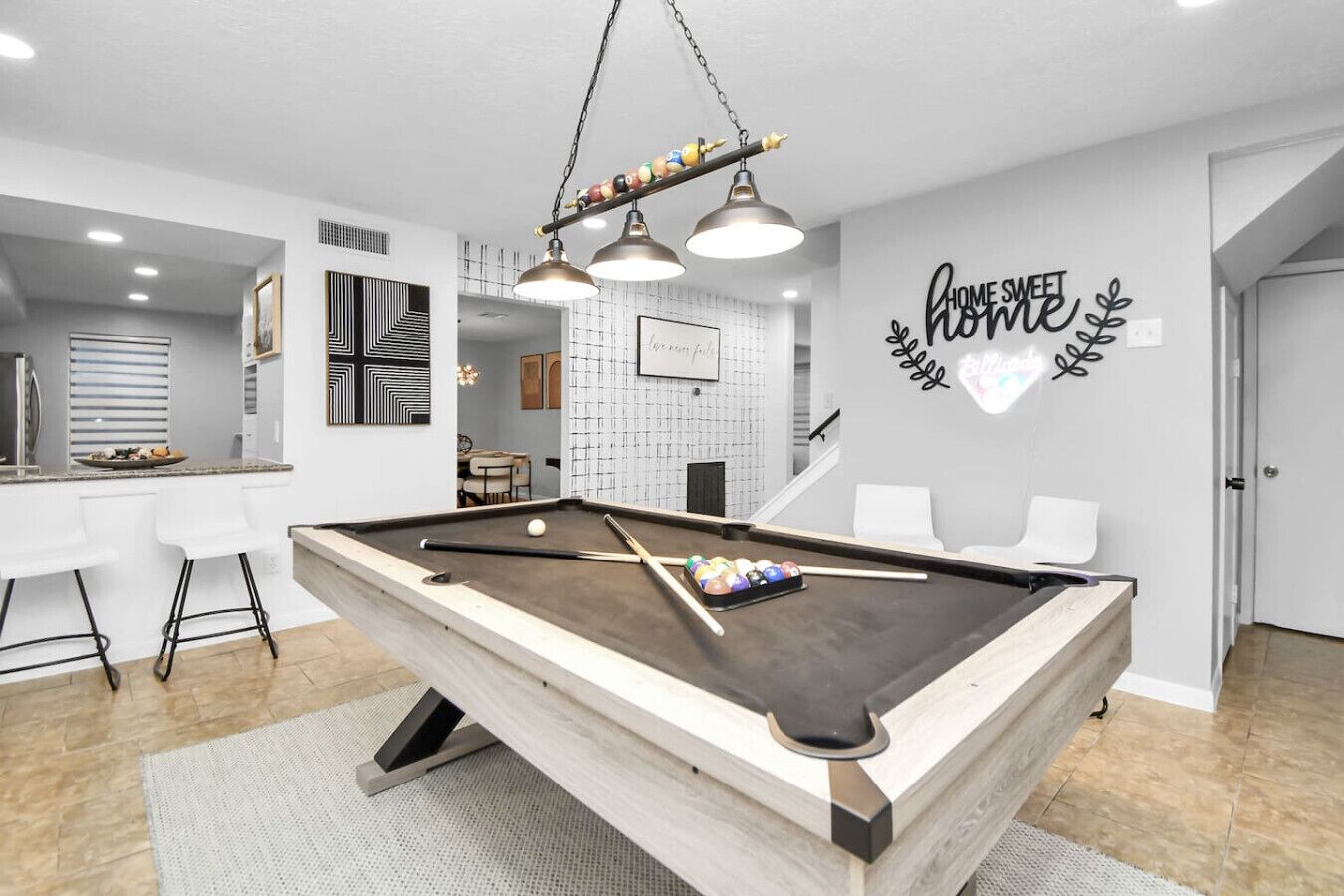 A modern living room with a pool table, a bar area, and a dining space.