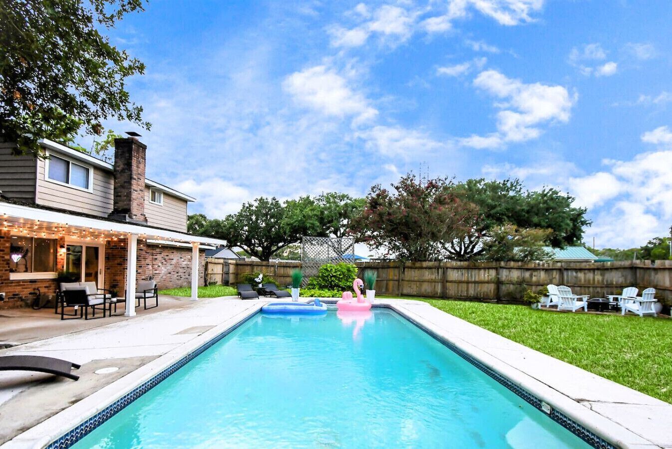 A backyard with a swimming pool, outdoor furniture, and a covered patio area.