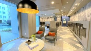 Un hall d’hôtel moderne doté d’un espace salon, d’une grande fenêtre et d’une rangée de casiers.