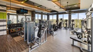 Une salle de sport moderne, dotée de divers appareils d’exercice, de grandes fenêtres et d’une enseigne bien visible sur laquelle on peut lire « fein ».