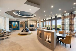 A modern hotel lobby with a reception desk, seating area, and large windows offering views.