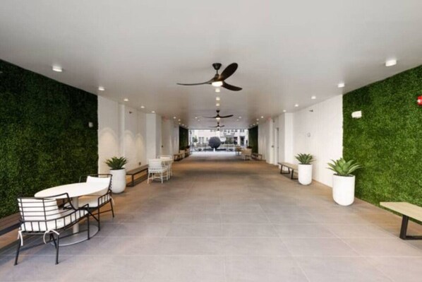 A spacious corridor with ceiling fans, potted plants, and seating areas.