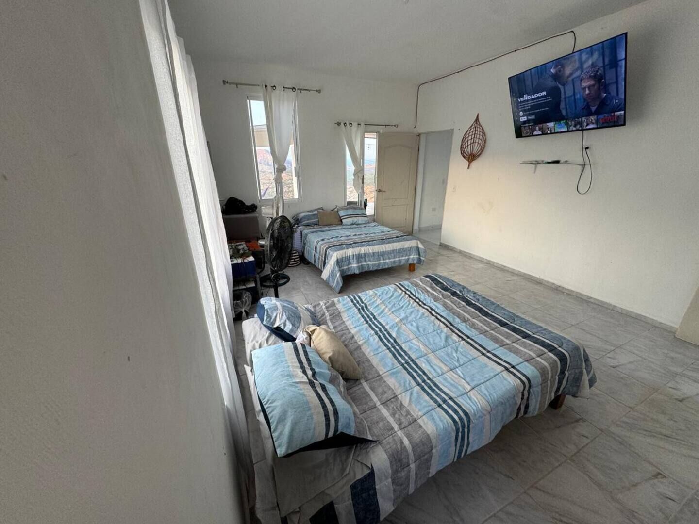 Habitació amb dos llits, televisió i ventilador.