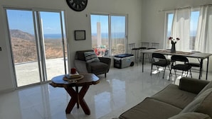 Un soggiorno spazioso con un divano ampio, un tavolo da pranzo con sedie e vista sul paesaggio attraverso ampie porte scorrevoli.