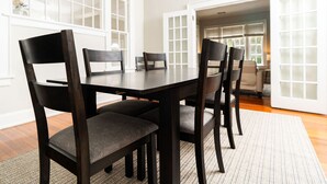 A dining area with a dark wooden table and chairs, white walls, and a view of a room with a window. - Hilton`s Luxe Retreat near Ft Benning & Downtown (Columbus)