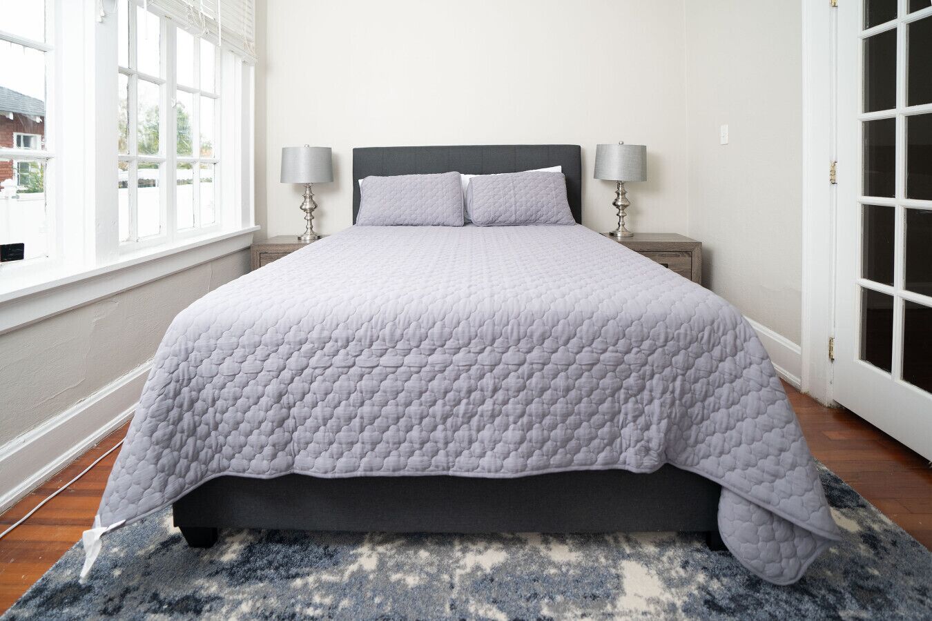 Een slaapkamer met een bed, twee bedlampen, een raam en een deur.