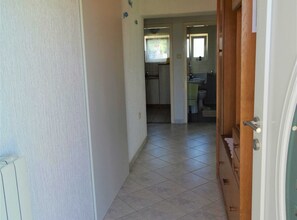Een gang die uitkomt bij een keuken met betegelde vloer en een zichtbare toilet.
