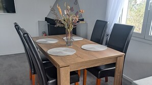 A dining table with four black chairs, a vase with dried flowers, and a modern kitchen in the background. - House by the sea (Salamina)