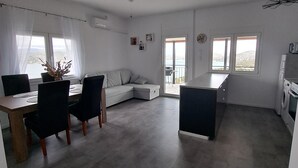 A spacious living area with a dining table, chairs, a sofa, and a ceiling fan. - House by the sea (Salamina)