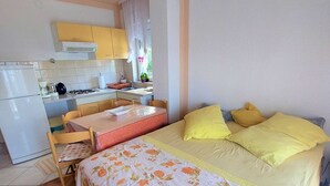 A compact bedroom with a bed, a small table, and a kitchenette. - Elegant Apartments with Sea View and Balcony - One Bedroom Apartment with Sea View and Balcony (Crikvenica)