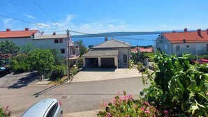 A residential street with houses, a garage, and a view of a lake. - Elegant Apartments with Sea View and Balcony - One Bedroom Apartment with Sea View and Balcony (Crikvenica)