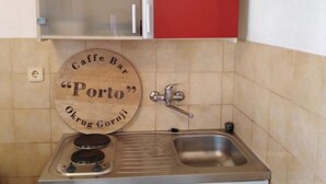 A kitchen with a sink, a stove, and a wooden sign that reads "Caffe Bar Porto".
