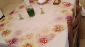 A table with a floral tablecloth, a green bottle, and two glasses.