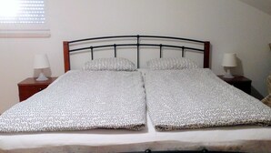 A bed with a metal frame, two pillows, and a patterned bedspread.