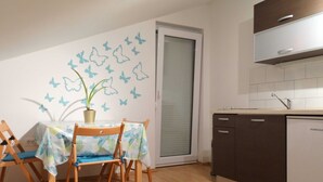 A compact kitchen with a dishwasher, a dining area with a table and chairs, and a door with a frosted glass panel.