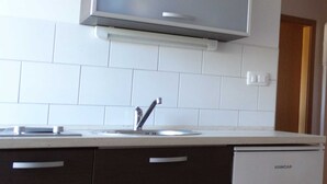 A kitchen with white tiles, a built-in sink, and a Koncar dishwasher.