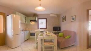 A compact kitchen with a dining area, a sofa, and a television. - Apartments Jukica - Three Bedroom Apartment With Sea View (Vis)