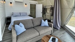 A cozy interior with a sofa, a small round table, and a bed in a tent-like structure.