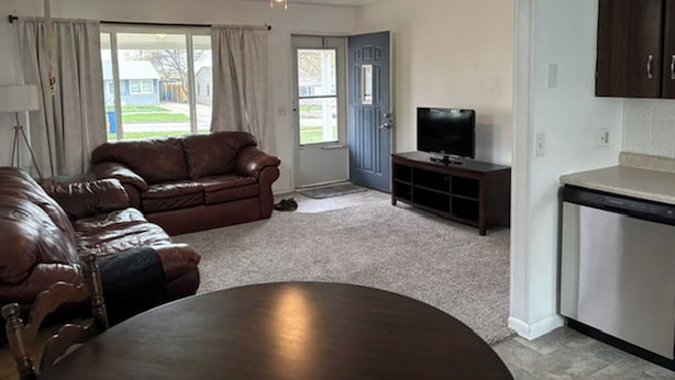 A living room with a brown leather sofa, a TV on a stand, and a dining table. - Family and Dog Friendly Modern Traditional Home in Rapid City South Dakota (Rapid City)