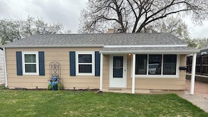 A single-story house with a beige exterior, dark shutters, and a front porch. - Family and Dog Friendly Modern Traditional Home in Rapid City South Dakota (Rapid City)