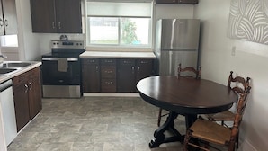A kitchen with dark wooden cabinets, a stainless steel refrigerator, a built-in oven, and a dining table with chairs. - Family and Dog Friendly Modern Traditional Home in Rapid City South Dakota (Rapid City)
