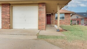 Une maison d’habitation avec un garage, une façade en briques et un porche couvert.